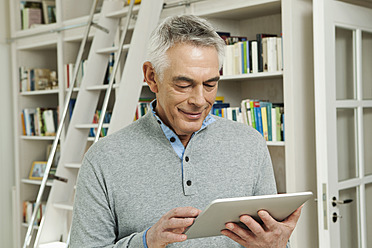 Germany, Berlin, Senior man using tablet pc, smiling - FMKYF000009