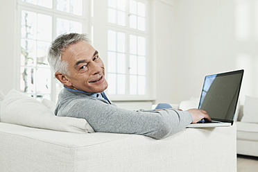 Germany, Berlin, Senior man using laptop, portrait - FMKYF000020