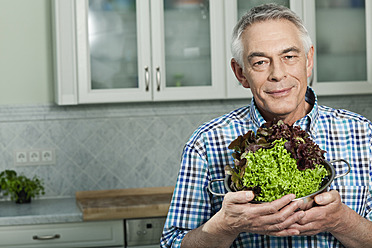 Germany, Berlin, Senior man holding vegetables, portrait - FMKYF000027