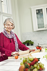 Germany, Berlin, Senior woman preparing food, smiling, portrait - FMKYF000067