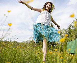 Austria, Young woman running in field of flowers - WWF002425