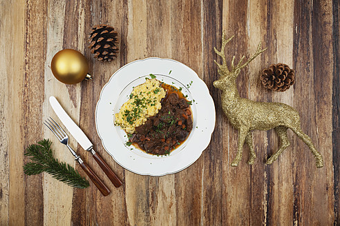 Teller mit gekochtem Hirschgulasch mit Kartoffelpüree und Weihnachtsdekoration auf Holzhintergrund - GWF001830