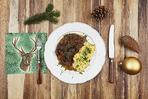 Teller mit gekochtem Hirschgulasch mit Kartoffelpüree und Weihnachtsdekoration auf Holzhintergrund - GWF001822