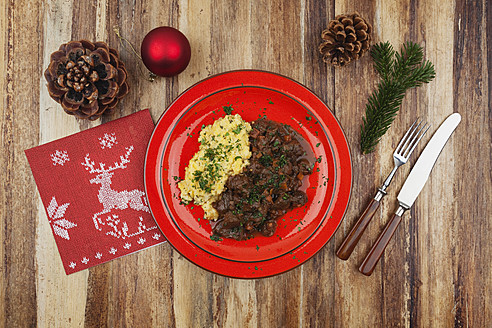 Teller mit gekochtem Hirschgulasch mit Kartoffelpüree und Weihnachtsdekoration auf Holzhintergrund - GWF001817