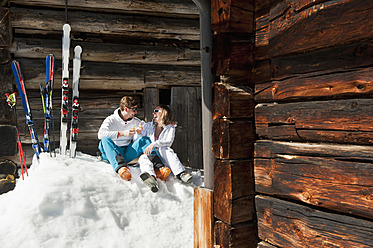 Österreich, Salzburg, Junges Paar sitzt vor einer Almhütte - HHF004189