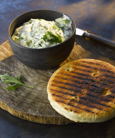 bowl of tzatziki with grilled bread on wooden board, close up stock photo