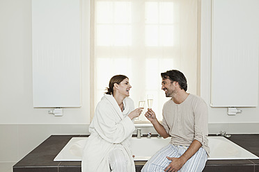 Deutschland, Berlin, Älteres Paar sitzt mit Sekt in der Badewanne - FMKYF000087