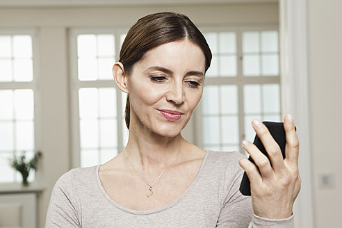 Germany, Berlin, Mature woman looking at mobile phone - FMKYF000100