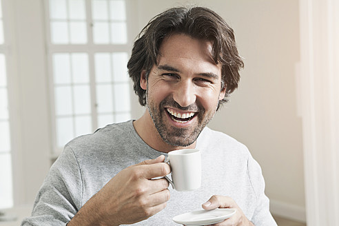 Deutschland, Berlin, Älterer Mann mit Kaffeetasse, lächelnd, Porträt - FMKYF000110