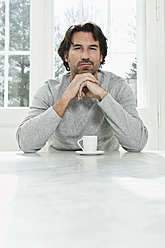 Germany, Berlin, Mature man with coffee cup, portrait - FMKYF000111