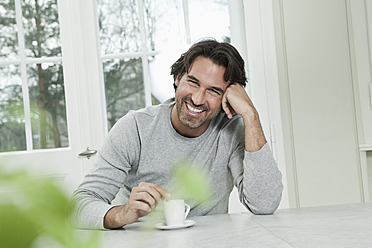 Deutschland, Berlin, Älterer Mann mit Kaffeetasse, lächelnd, Porträt - FMKYF000113