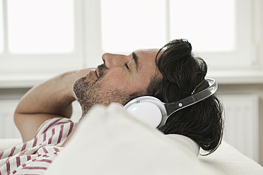 Germany, Berlin, Mature man listening music with head phones - FMKYF000119