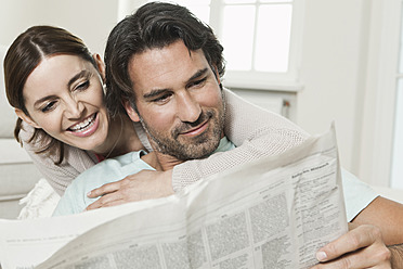 Germany, Berlin, Mature couple reading newspaper, smiling - FMKYF000122