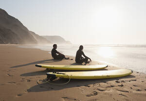 Portugal, Paar am Strand sitzend mit Surfbrett - MIRF000460