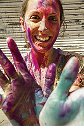 India, Ahmedabad, Young woman with colourfull hands and face on holi festival - MBEF000351