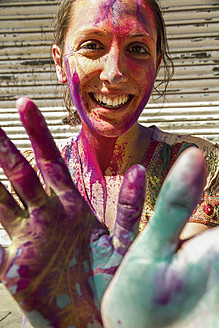 Indien, Ahmedabad, Junge Frau mit bunten Händen und Gesicht auf dem Holi-Fest - MBEF000351
