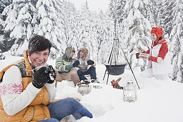 Austria, Salzburg, Men and women sitting at fire place in winter - HHF004211