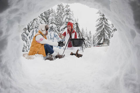 Austria, Salzburg, Young women sitting at fire place in winter stock photo