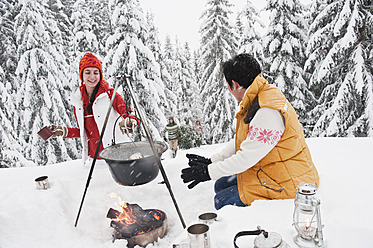 Austria, Salzburg, Man and woman by fireplace, people carrying christmas tree in background - HHF004229