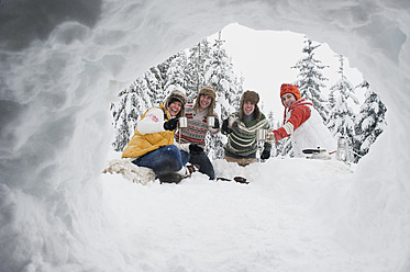 Österreich, Salzburg, Männer und Frauen sitzen am Kamin im Winter - HHF004219