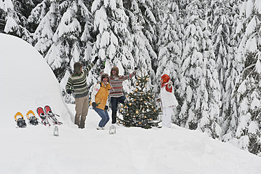 Austria, Salzburg, Men and women dancing by christmas tree in winter - HHF004223