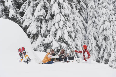 Austria, Salzburg, Men and women sitting at fire place in winter stock photo