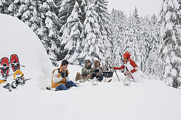 Austria, Salzburg, Men and women sitting at fire place in winter - HHF004230