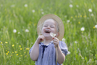 Germany, Bavaria, Girl with dandelion seed, smiling - TCF002750