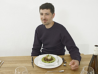 Germany, Cologne, Mid adult man having dinner in kitchen, smiling, portrait - RHYF000151