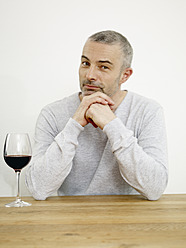 Germany, Cologne, Mature man with wine in kitchen, portrait - RHYF000179