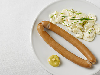 Ein Paar Würstchen mit Kartoffelsalat und Senf in einem Teller auf weißem Hintergrund - KSWF000880