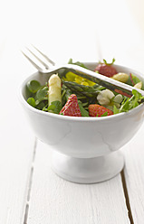 Herbs salad with asparagus and strawberries in bowl, close-up - KSWF000916