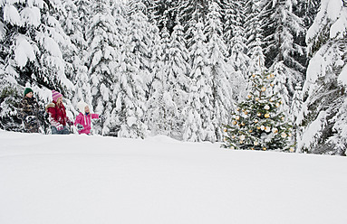 Österreich, Land Salzburg, Junge und Mädchen gehen durch den Schnee und betrachten den Weihnachtsbaum - HHF004255