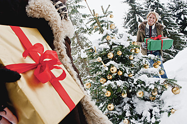 Österreich, Land Salzburg, Paar hält Weihnachtsgeschenk im Schnee - HHF004265