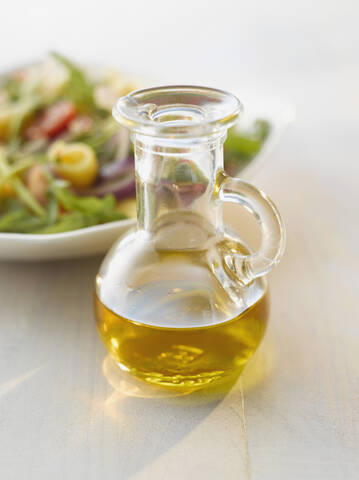 Ölflasche vor einem Salat, lizenzfreies Stockfoto