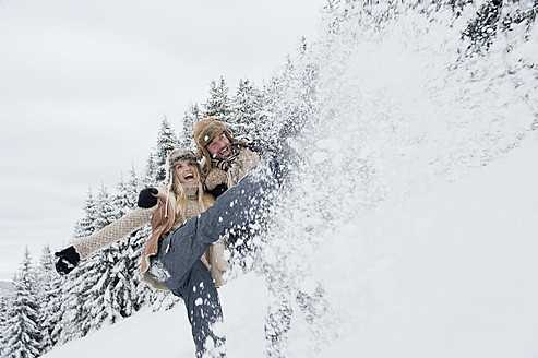 Austria, Salzburg County, Couple splashing snow in snowy landscape,smiling - HHF004283