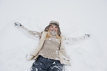 Austria, Salzburg County, Mid adult woman lying on snow, smiling - HHF004285