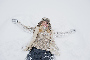 Österreich, Land Salzburg, Mittlere erwachsene Frau im Schnee liegend, lächelnd - HHF004285