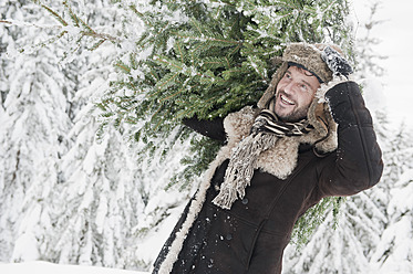 Österreich, Land Salzburg, Älterer Mann mit Weihnachtsbaum, lächelnd - HHF004287