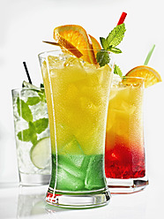 Gläser mit geeistem Orangensaft, Tequila Sunrise und Mojito auf weißem Hintergrund - KSWF000987
