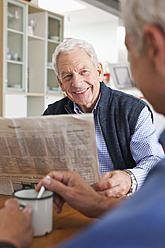 Deutschland, Leipzig, Älterer Mann liest Zeitung, ein anderer Mann rührt Kaffee um - WESTF018736