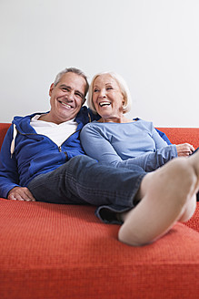 Deutschland, Leipzig, Älterer Mann und Frau entspannen sich auf der Couch, lächelnd - WESTF018779