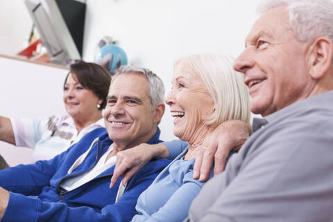 Germany, Leipzig, Senior men and women sitting on couch, smiling stock photo