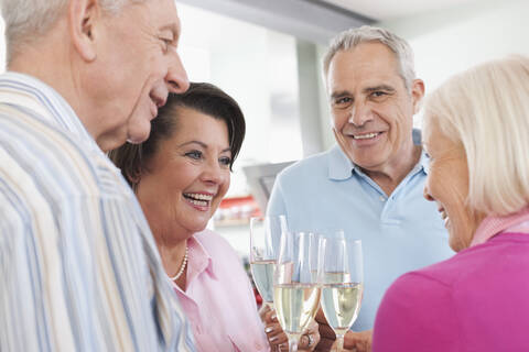 Germany, Leipzig, Senior men and women drinking sparkling wine, smiling stock photo