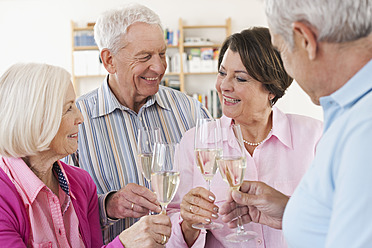 Germany, Leipzig, Senior men and women drinking sparkling wine, smiling - WESTF018812