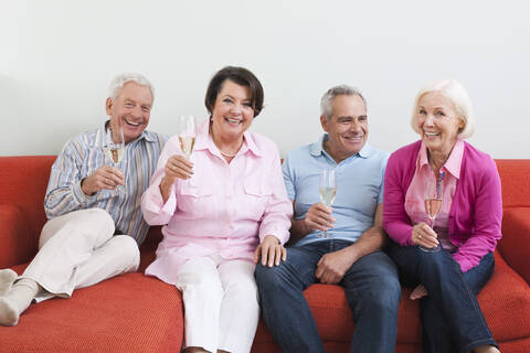 Germany, Leipzig, Senior men and women drinking sparkling wine, smiling stock photo