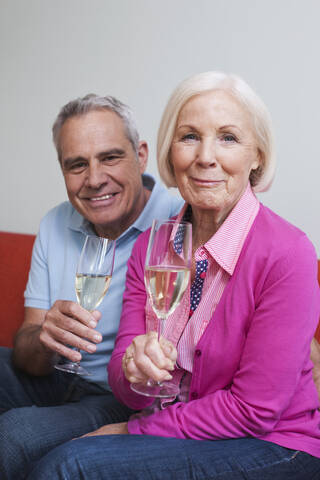 Deutschland, Leipzig, Älterer Mann und Frau trinken Sekt, lächelnd, lizenzfreies Stockfoto