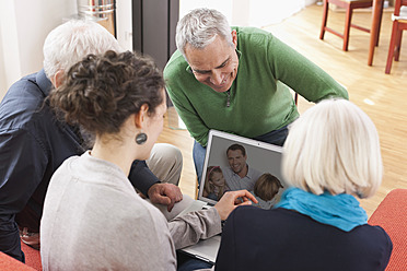 Deutschland, Leipzig, Männer und Frauen schauen sich Bilder auf dem Laptop an - WESTF018868