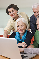 Deutschland, Leipzig, Ältere Männer und Frauen sehen sich Bilder auf einem Laptop an - WESTF018872