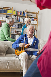 Deutschland, Leipzig, älterer Mann spielt E-Gitarre, Mann und Frau im Hintergrund - WESTF018886